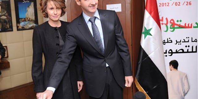 Syrian President Bashar Assad casts his ballot next to his wife Asma at a polling station during a referendum on the new constitution, in Damascus, Syria, on Feb. 26, 2012.