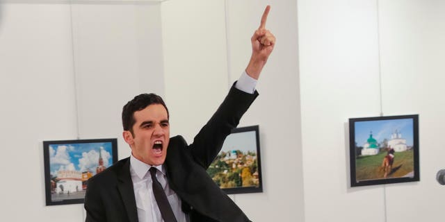 FILE - In this Monday, Dec. 19, 2016 file photo, Mevlut Mert Altintas shouts after shooting Andrei Karlov, right, the Russian ambassador to Turkey, at an art gallery in Ankara, Turkey. At first, AP photographer Burhan Ozbilici thought it was a theatrical stunt when a man in a dark suit and tie pulled out a gun during the photography exhibition. The man then opened fire, killing Karlov. (AP Photo/Burhan Ozbilici)