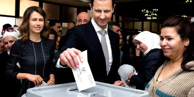 This photo released on the official Facebook page of Syrian Presidency, shows Syrian President Bashar Assad casting his ballot in the parliamentary elections in 2016, as his wife Asma, left, is standing next to him, in Damascus.