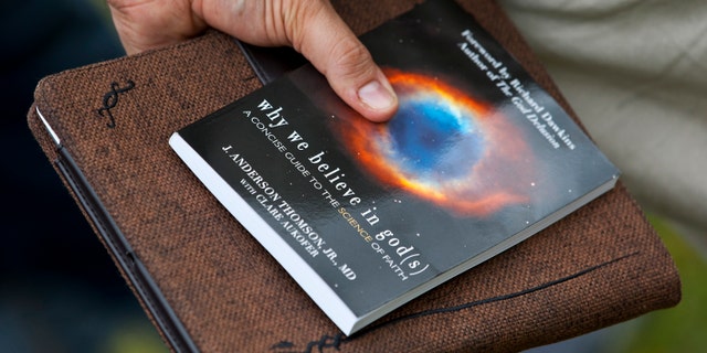 A supporter talks to Richard Dawkins, a well-known atheist and best-selling author, while holding a copy of his book during an atheist-themed festival at Fort Bragg army base in North Carolina.