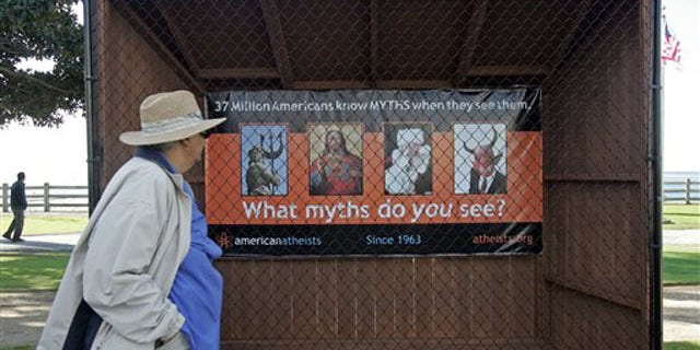 A woman walks past a sign displaying an Atheist message along Ocean Avenue at Palisades Park in Santa Monica, Calif. Tuesday, Dec. 13, 2011.