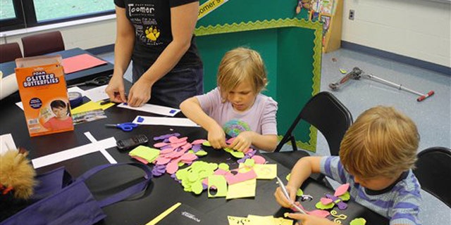 In this Thursday, Aug. 4, 2011 photo, Parent volunteer Trinity Laurino, left, works on bulletin board decorations at Toomer Elementary School in Atlanta with her daughter, Olivia Laurino, center, and friend, Jake Jonsson in Atlanta. Atlanta Public Schools returns to classes Monday, Aug. 8, 2011.