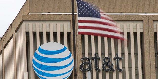 File photo - An AT&T Logo is pictured as a U.S. flag flutters in the foreground in Pasadena, Calif., Jan. 26, 2015. (REUTERS/Mario Anzuoni)