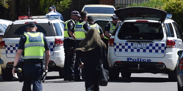 Police accompany a woman as they attend the scene where a house was raided at Meadow Heights in Melbourne, Australia, Friday, Dec. 23, 2016.
