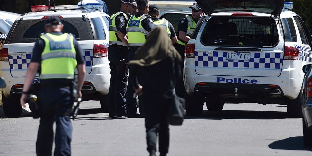 Police accompany a woman as they attend the scene where a house was raided at Meadow Heights in Melbourne, Australia, Friday, Dec. 23, 2016.