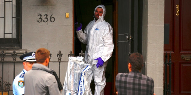 A police officer wearing protective gear talks to fellow officers as he stands in the doorway of a home after Australian counter-terrorism police arrested four people in raids.
