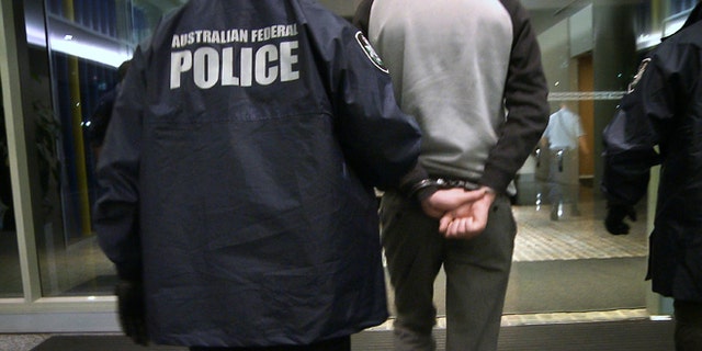 April 23, 2013: In this photo provided by the Australian Federal Police, a handcuffed man is escorted by police following his arrest on a charge of attacking and defacing a government website. The Australian man, who police say has claimed to be a high-level member of international hacking collective Lulz Security, was charged with two counts of unauthorized modification of data to cause impairment, and one count of unauthorized access to, or modification of, restricted data.