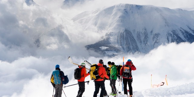 Rescuers stand near an avalanche site near Fiesch, Switzerland, Sunday, April 1, 2018.