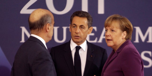 Nov. 2, 2011: French President Nicolas Sarkozy, center, and French Foreign Minister Alain Juppe, left, welcome German Chancellor Angela Markel at the G20 summit in Cannes.