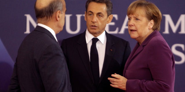 Nov. 2, 2011: French President Nicolas Sarkozy, center, and French Foreign Minister Alain Juppe, left, welcome German Chancellor Angela Markel at the G20 summit in Cannes.