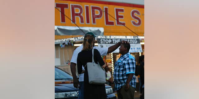 Darin Fontenette, left, football coach for Na'Quincy Pierson, son of Alton Sterling, pats Na'Quincy on the head outside the Triple S Food Mart, where Sterling was killed last year in Baton Rouge, La., Tuesday, May 2, 2017. The U.S. Justice Department has decided not to charge two white Baton Rouge police officers in the death of Sterling, whose death was captured on cell phone video, fueling protests in Louisiana's capital and beyond. (AP Photo/Gerald Herbert)