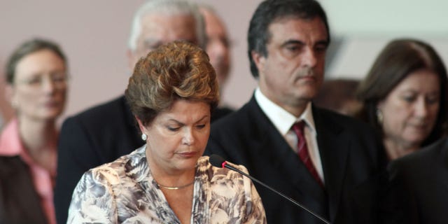 Brazil's President Dilma Rousseff, front, stands a minute of silence for the victims of a deadly fire at a nightclub during a meeting with mayors who recently took office in Brasilia, Brazil, Monday, Jan. 28, 2013. A blaze raced through a crowded nightclub in southern Brazil early Sunday, killing more than 230 people as the air filled with deadly smoke and panicked party-goers stampeded toward the exits, police and witnesses said. (AP Photo/Eraldo Peres)