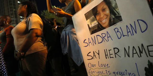 A demonstrator holds a Sandra Bland sign during a vigil, Tuesday evening, July 28, 2015, near the DuSable Bridge on Michigan Ave. in Chicago. Bland died in a Texas county jail after the traffic stop for failing to use a turn signal escalated into a physical confrontation. Authorities have said Bland hanged herself, a finding her family disputes. The death has garnered national attention amid increased scrutiny of police treatment of blacks in the wake of several high-profile police-involved deaths. (AP Photo/Christian K. Lee)