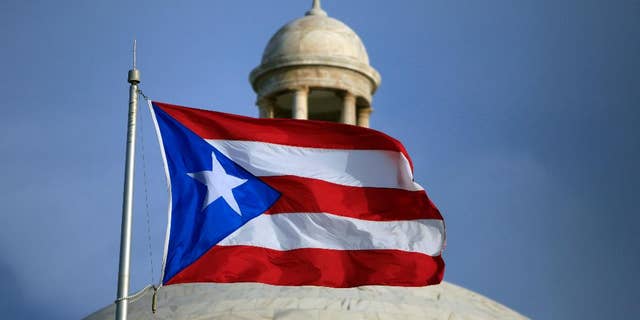 FILE - In this Wednesday, July 29, file 2015 photo, the Puerto Rican flag flies in front of Puerto Rico’s Capitol as in San Juan, Puerto Rico. On Monday, April 11, 2016, Puerto Rico released a new proposal to restructure part of its $70 billion debt to buy time to implement a fiscal growth plan as multimillion-dollar payments loom for a U.S. territory facing dwindling cash reserves. (AP Photo/Ricardo Arduengo, File)