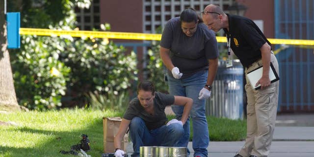 San Diego's Metro Arson Strike Team and SDPD homicide team on July 6 gathering evidence from the sidewalk and grassy area where a homeless person was attacked.