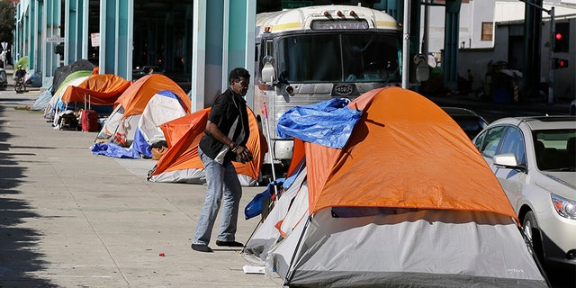 A man stands outside his tent on Division Street in San Francisco.