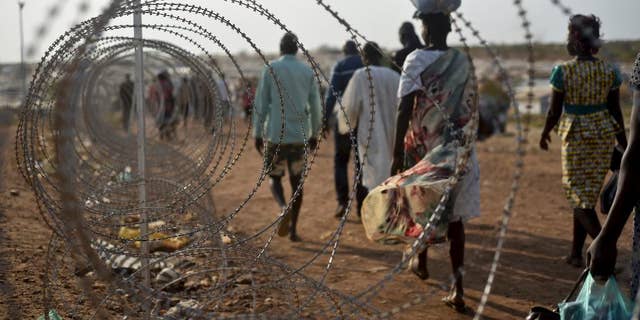 FILE - In this Tuesday Jan. 19, 2016 file photo, displaced people walk next to a razor wire fence at the United Nations base in the capital Juba, South Sudan. A U.N. team of human rights investigators said Friday Dec. 2, 2016, that rape in South Sudan is one of the tools being used for ethnic cleansing, adding that sexual violence in the East African nation has reached epic proportions. (AP Photo/Jason Patinkin, File)