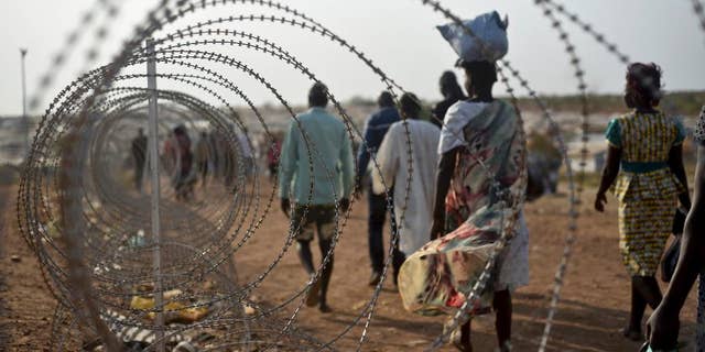 FILE - In this Tuesday Jan. 19, 2016 file photo, displaced people walk next to a razor wire fence at the United Nations base in the capital Juba, South Sudan. A U.N. team of human rights investigators said Friday Dec. 2, 2016, that rape in South Sudan is one of the tools being used for ethnic cleansing, adding that sexual violence in the East African nation has reached epic proportions. (AP Photo/Jason Patinkin, File)