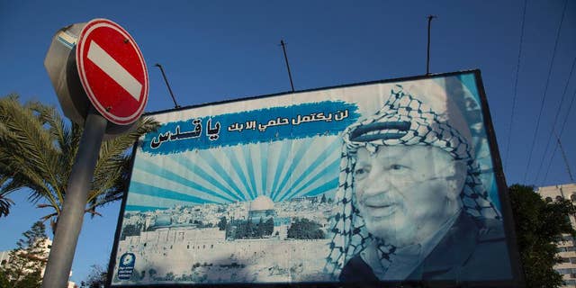 A billboard with a picture of the former Palestinian leader Yasser Arafat is seen with Arabic writing that reads, "My dream will not be complete without Al-Quds," in Gaza City, Sunday, Nov. 9, 2014. The Hamas militant group on Sunday forced the cancellation of a memorial ceremony that was to have marked the 10th anniversary of the death of Palestinian leader Yasser Arafat, underscoring the lingering tensions with the rival Fatah movement despite the formation of a unity government meant to end years of hostilities. (AP Photo/Khalil Hamra)