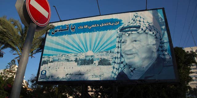 A billboard with a picture of the former Palestinian leader Yasser Arafat is seen with Arabic writing that reads, "My dream will not be complete without Al-Quds," in Gaza City, Sunday, Nov. 9, 2014. The Hamas militant group on Sunday forced the cancellation of a memorial ceremony that was to have marked the 10th anniversary of the death of Palestinian leader Yasser Arafat, underscoring the lingering tensions with the rival Fatah movement despite the formation of a unity government meant to end years of hostilities. (AP Photo/Khalil Hamra)