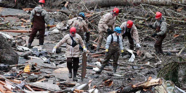 Workers comb through debris at the site of a deadly mudslide, Friday, March 28, 2014, in Oso, Wash. Besides the 26 bodies already found, dozens more people could be buried in the debris pile left from the mudslide nearly one week ago. (AP Photo/Lindsey Wasson, Pool)