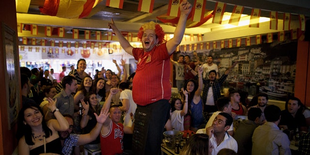 MADRID, SPAIN - JUNE 13: A waiter cheers up Spanish soccer fans watching their team playing against the Netherlands in a Madrid tavern during Spain's first FIFA World Cup match on June 13, 2014 in Madrid, Spain. Spain are the current Champions after they won 2010 World Cup final against Holland, but today they lost the match 5-1. (Photo by Pablo Blazquez Dominguez/Getty Images)