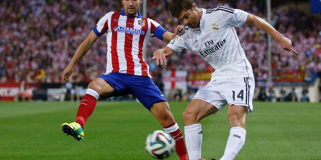 Real Madrid Xabi Alonso right, duels for the ball with Atletico Madrid's Gabi during a Spanish Super Cup soccer match at the Vicente Calderon stadium in Madrid, Spain, Friday, Aug. 22, 2014. (AP Photo/Daniel Ochoa de Olza)