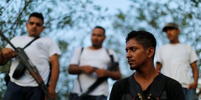 Men belonging to a self-defense group stand at a checkpoint in the town of Las Colonias, Mexico, Tuesday, Nov. 5, 2013. Two leaders of the main vigilante groups in western Michoacan state said Tuesday that they are pulling back from confronting the Knights Templar drug cartel because the Mexican government has promised to oust traffickers from the area. (AP Photo/Dario Lopez-Mills)