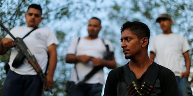 Men belonging to a self-defense group stand at a checkpoint in the town of Las Colonias, Mexico, Tuesday, Nov. 5, 2013. Two leaders of the main vigilante groups in western Michoacan state said Tuesday that they are pulling back from confronting the Knights Templar drug cartel because the Mexican government has promised to oust traffickers from the area. (AP Photo/Dario Lopez-Mills)