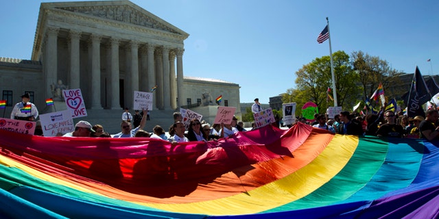 FILE - In this April 28, 2015, file photo, demonstrators stand in front of a rainbow flag of the Supreme Court in Washington, as the court was set to hear historic arguments in cases that could make same-sex marriage the law of the land. Gay and lesbian couples could face legal chaos if the Supreme Court rules against same-sex marriage in the next few weeks. Same-sex weddings could come to a halt in many states, depending on a confusing mix of lower-court decisions and the sometimes-contradictory views of state and local officials. Among the 36 states in which same-sex couples can now marry are 20 in which federal judges invoked the Constitution to strike down marriage bans. (AP Photo/Jose Luis Magana, File)