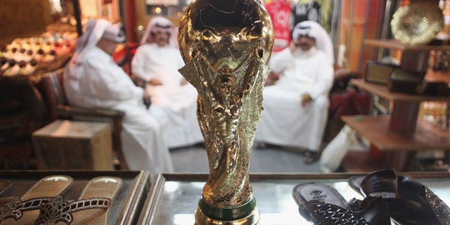 DOHA, QATAR - OCTOBER 24: Arab men sit at a shoemaker's stall with a replica of the FIFA World Cup trophy in the Souq Waqif traditional market on October 24, 2011 in Doha, Qatar. Qatar will host the 2022 FIFA World Cup football competition and is slated to tackle a variety of infrastructure projects, including the construction of new stadiums. (Photo by Sean Gallup/Getty Images)