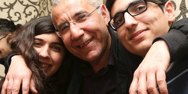Human rights activist Intigam Aliyev, center, poses for a photo with his son and daughter upon his release at home in Baku, Azerbaijan, Monday, March 28, 2016. A court in Azerbaijan has ordered the release of a human rights activist who spent the last two years in jail. Aliyev was convicted last year of economic crimes that critics have dismissed as retaliation for his work. (AP Photo/Aziz Karimov)