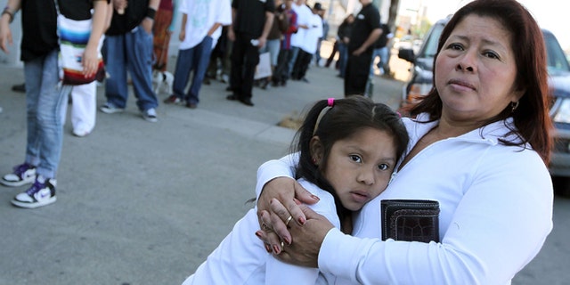 OAKLAND, CA - APRIL 30: A woman embraces her child as they watch the group "Youth United For Justice" protest Arizona's new immigration law April 30, 2010 in Oakland, California. Dozens of people marched in protest of Arizona state bill 1070 which was signed into law this past week and gives law enforcement officials unprecedented authority to stop and question suspected illegal immigrants. (Photo by Justin Sullivan/Getty Images)