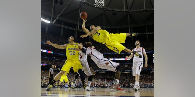 FILE - In this April 8, 2013 file photo, Michigan guard Trey Burke (3) shoots over Louisville center Gorgui Dieng (10) during the second half of the NCAA Final Four tournament college basketball championship game in Atlanta. Burke is honored as the Wooden Award winner Friday April 12, 2013 in Los Angeles. (AP Photo/Charlie Neibergall, File)