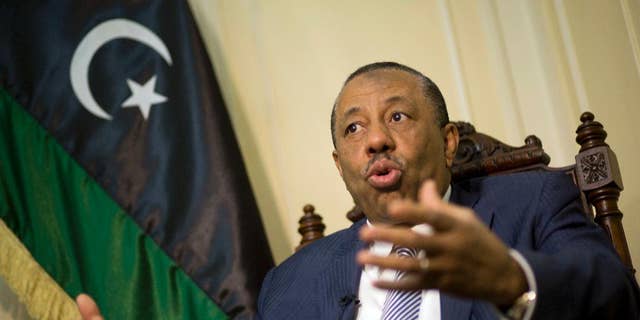 Libyan Prime Minister Abdullah al-Thinni, speaks during an interview with the Associated Press at the Libyan embassy in Cairo, Egypt, Tuesday, July 5, 2016. Al-Thinni of the interim government based in the eastern region, told The Associated Press that the UN-brokered deal has reached a deadlock. The deal must be amended, he said. Libyan flag seen at background.(AP Photo/Amr Nabil)