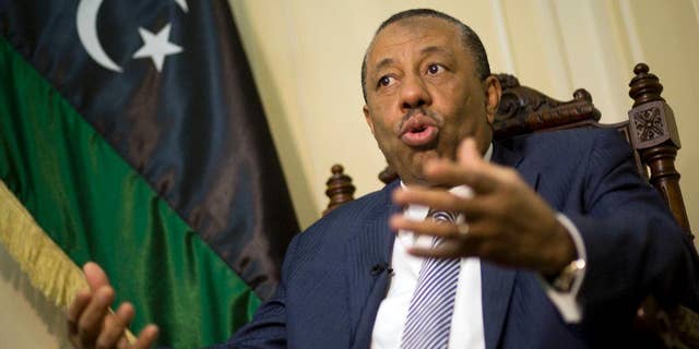 Libyan Prime Minister Abdullah al-Thinni, speaks during an interview with the Associated Press at the Libyan embassy in Cairo, Egypt, Tuesday, July 5, 2016. Al-Thinni of the interim government based in the eastern region, told The Associated Press that the UN-brokered deal has reached a deadlock. The deal must be amended, he said. Libyan flag seen at background.(AP Photo/Amr Nabil)