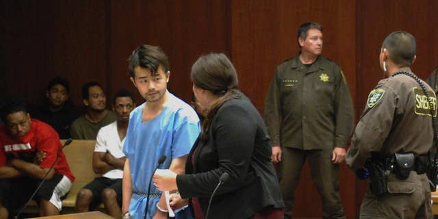 Yu Wei Gong, left, speaks to Deputy Public Defender Diamond Grace in court in Honolulu on Monday, April 17, 2017. The Hawaii man accused of killing his mother months ago stuffed her decapitated head and dismembered body parts in several plastic bags in the refrigerator freezer of the Waikiki apartment they shared, according to court documents made public ahead of the suspect's first court appearance. (AP Photo/Jennifer Sinco Kelleher)