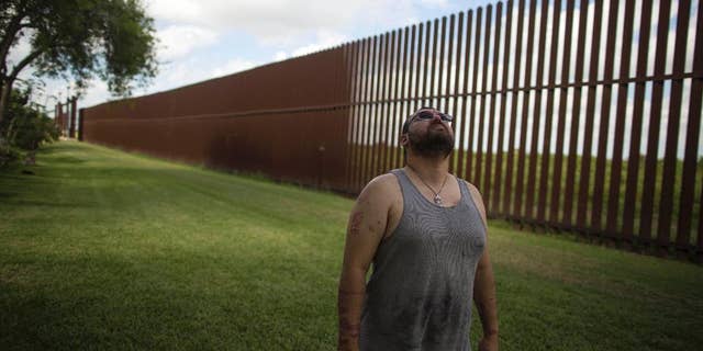 FILE - In this March 22, 2017, file photo, Antonio Reyes of Brownsville, Texas, stands by the U.S.-Mexico border fence near his home. (AP Photo/Rodrigo Abd, File)