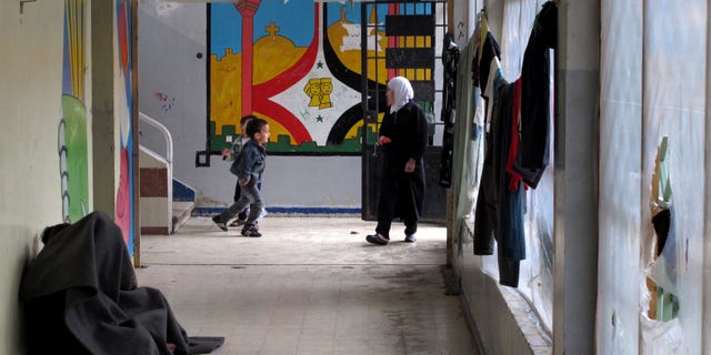 Children whose families have fled their homes to escape fighting in Syria's civil war huddle under blankets for warmth in a hallway in an elementary school that has been turned into a shelter in Damascus, Syria, Thursday, Dec. 5, 2013. Around 44 families live in the school, just one set up as Syria deals with more than 5 million displaced people on its soil. (AP Photo/Lee Keath)