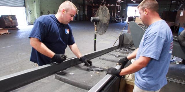 Operators examine destroyed weapons fragments after the pieces exit Captain Crunch's shredder.