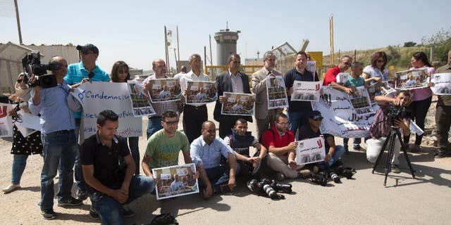 Palestinian journalists hold banners during a protest calling for the release of Palestinian journalist Omar Nazzal, who was arrested by Israeli authorities over the weekend, outside Ofer military prison near the West Bank city of Ramallah, Tuesday, April 26, 2016. (AP Photo/Majdi Mohammed)