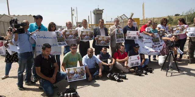 Palestinian journalists hold banners during a protest calling for the release of Palestinian journalist Omar Nazzal, who was arrested by Israeli authorities over the weekend, outside Ofer military prison near the West Bank city of Ramallah, Tuesday, April 26, 2016. (AP Photo/Majdi Mohammed)