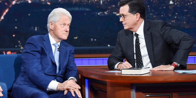 Former President Bill Clinton, left, appears with host Stephen Colbert while promoting his book 'The President is Missing,' on 'The Late Show with Stephen Colbert,' Tuesday, June 5, 2018 in New York.