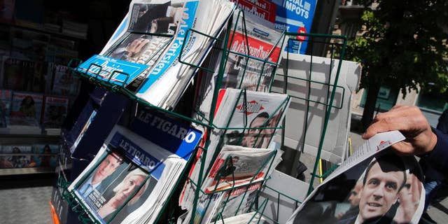A man takes a French national newspaper reporting on the winners of the first round of the French presidential election, centrist candidate Emmanuel Macron and far-right candidate Marine Le Pen, on a newsstand in Paris, France, Monday, April 24, 2017. French voters shut out the country's political mainstream from the presidency for the first time in the country's modern history, and on Monday found themselves being courted across the spectrum for the runoff election. (AP Photo/Christophe Ena)