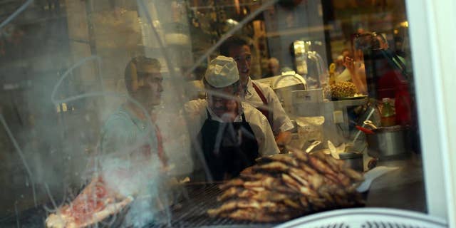 A man grills meat in a barbecue of a Portuguese traditional food restaurant in Lisbon, Thursday, May 21, 2015. European Central Bank head Mario Draghi said that "growth is too low everywhere" in Europe despite a modest recovery, during an ECB's conference on inflation and unemployment in Sintra, Portugal. (AP Photo/Francisco Seco)