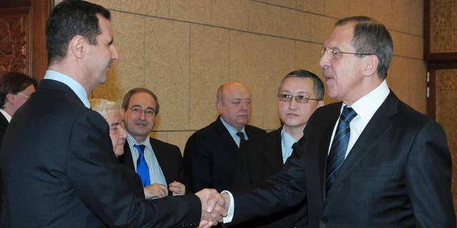 FILE - In this Feb. 7, 2012 file photo, Syrian President Bashar Assad, left, shakes hands with Russian Foreign Minister Sergey Lavrov after talks in Damascus, Syria. Lavrov said Thursday, Sept. 10, 2015, that Russian aircraft flying into Syria have been delivering weapons along with humanitarian supplies. (AP Photo/Pool, File)