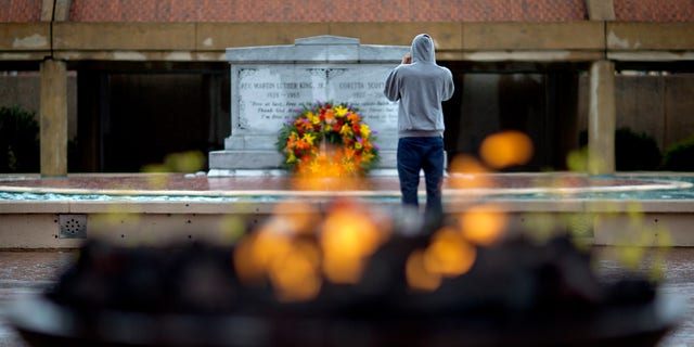 A visitor stands in front of the grave of Martin Luther King, Jr., as an eternal flame burns in the foreground on the 45th anniversary of the assassination of the civil rights leader, Thursday, April 4, 2013, in Atlanta. (AP Photo/David Goldman)