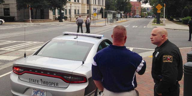Law enforcement officers gather outside police headquarters in Charlotte, N.C., on Tuesday, Sept. 27, 2016, after a suspicious package was found inside the building. A city spokesman says the structure was evacuated and searched as a precaution following days of protests over the fatal police shooting of a black man. (AP Photo/Jay Reeves)