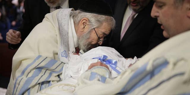 FILE- In this Feb. 11, 2015 file photo, Abraham Romi Cohn performs the oral suction during the bris, or ritual circumcision, of Yosef Sananas in New York. Reversing a policy that pitted health officials against religious leaders over a practice that dates to biblical times, the New York City Board of Health will no longer require parents to sign acknowledgements of potential health risks when their children undergo oral circumcision, Wednesday, Sept. 9, 2015. (AP Photo/Seth Wenig, File)