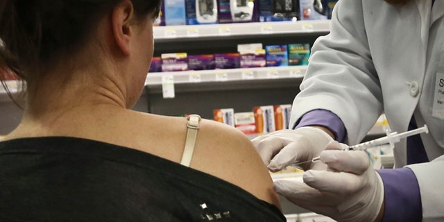 A pharmacy manager for Walgreens administers a flu vaccine on site.